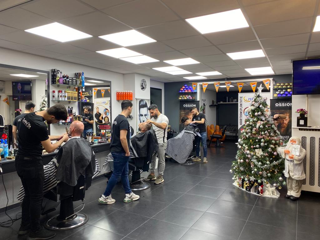 Een drukke dag in de zaak: barbers aan het werk aan de rij stoelen